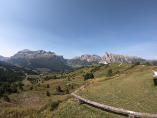 The sunlight dances on the meadows and ridges of the Dolomites, creating a mesmerizing play of light and shadow across the landscape.