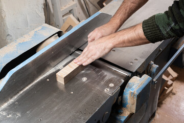 A carpenter processes an ash item on a electric jointer