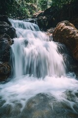 Obraz premium A serene waterfall surrounded by lush greenery and dense forest foliage