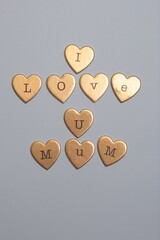 "I LOVE U MUM" on a gray background. Each heart has a single letter engraved on it, forming a heartfelt message. © Elvis