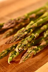 Green fresh asparagus from the garden lies on a wooden board on the table