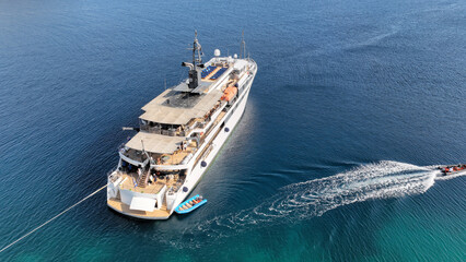 Aerial drone photo of luxury yacht anchored in tropical exotic island bay with emerald sea and secluded sandy beaches
