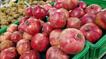 Ripe pomegranate fruits for sale in a supermarket. Pomegranate fruits close-up with selective focus. Berry-like fruit. Pile of delicious pomegranates for sale in a store. Variety of fresh produce