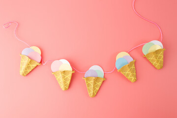 DIY ice cream cone craft made from recycled egg carton and colorful paper. Step-by-step creative process of making handmade party decoration. Flat lay composition on pink