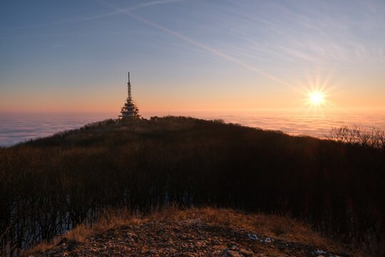 Transmitter during foggy sunrise. Telecommunications tower on mountain top at the sunrise. Zobor peak, dominant over the city Nitra, Slovakia