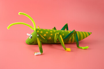 Fototapeta premium DIY grasshopper craft made from recycled materials, including painted cardboard tube, pipe cleaners, and googly eyes. Perfect for kids activities, craft projects, and educational initiatives
