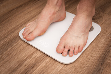 Close-up of a man's feet standing on a scale, checking body weight. Perfect for topics on health, fitness, weight loss, dieting, and wellness.