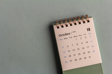 Desk calendar for October 2025 on a gray background.