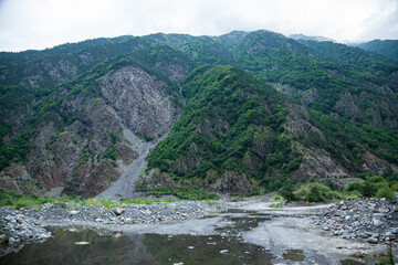Georgian green rocky mountains and a small river at the foot.