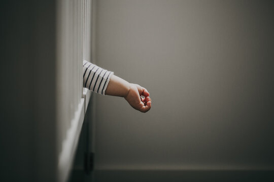 Close-up of a Baby boy's hand hanging out of the side of a cot