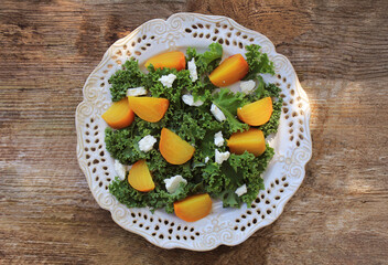 Healthy orange beet salad with fresh kale lettuce,  feta cheese on wooden table