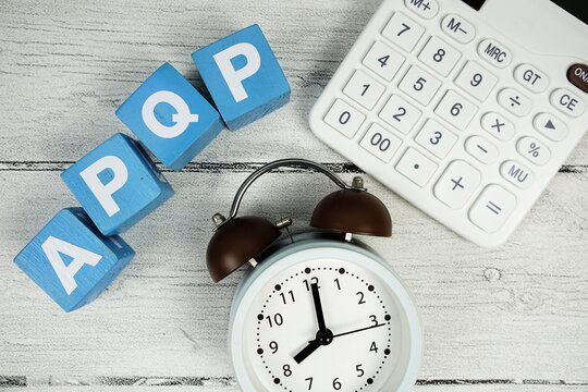 APQP (Advanced Product Quality Planning) text with alarm clcok and calculator on wooden background