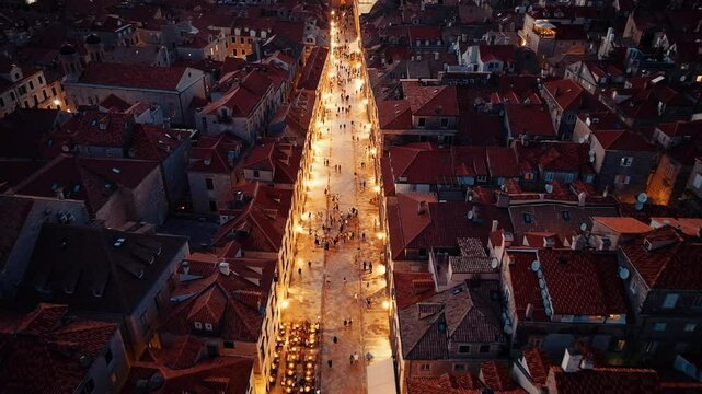 The street and human traffic running east-west in the middle. The lighting of the buildings on both sides of the Stradun emphasizes the historical texture of the street.