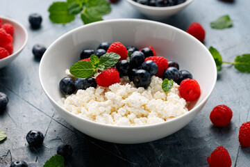 Bowl of cottage cheese, curd cheese with blueberry and raspberry. High protein healthy breakfast or lunch
