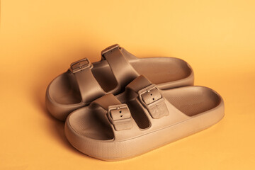 Beige brown rubber sandals on a yellow background close-up, for every day warm weather wear indoors or outdoors on the beach isolated 