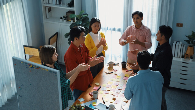 Top view of creative team clapping hands to celebrate increasing sales or successful idea. Group of diverse people brainstorming marketing plan by using sticky note while clapping hands.Convocation. - Powered by Adobe