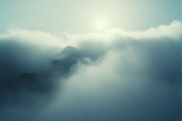 Obraz premium Sun peeks through clouds, creating a dreamlike scene of mountains and mist, capturing nature's beauty in ethereal hues.