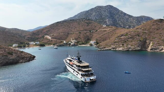 Aerial drone cinematic video of luxury yacht approaching small port of Thimena island untouched by tourism next to Fourni island, North Aegean sea, Greece