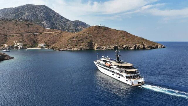 Aerial drone cinematic video of luxury yacht approaching small port of Thimena island untouched by tourism next to Fourni island, North Aegean sea, Greece