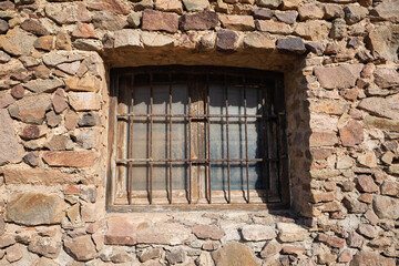 Vergittertes Holzfenster in einer alten Steinmauer