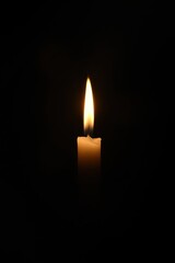 Fototapeta premium A single burning candle shines warmly in a dark space, symbolizing hope and faith during Christian observances like Maundy Thursday and Easter