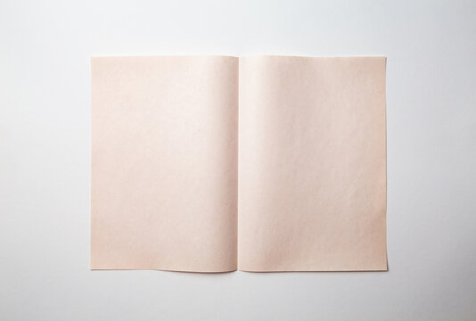 Mock up of a blank booklet with spread on a white background. Beige aged paper with a vertical fold in the middle.