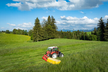 Grünfuttergewinnung im Allgäu - Traktor mit Mähwerk beim Gras mähen, Luftaufnahme. © Countrypixel