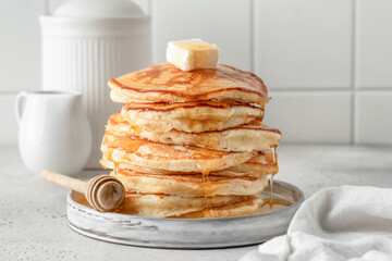 Homemade pancakes with honey an butter on top on white kitchen table background. Pancake day traditional meal