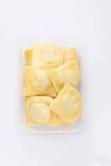 Close-up studio shot of an open plastic pack full of fresh Italian tortellini. Pack shot of transparent plastic box on white background