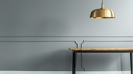 Golden pendant light fixture hangs elegantly beside an oak table with black legs in a modern interior with gray walls, emphasizing minimalist style.