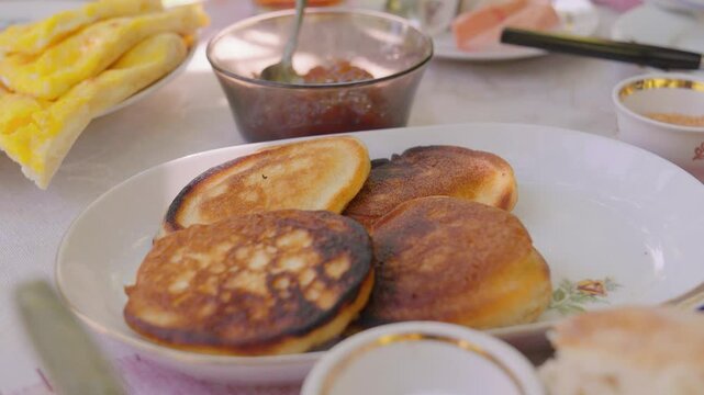 Sun-drenched outdoor stage with hearty homemade breakfast with golden amlet, khachapuri, freshly baked bread, crispy pastries, bright sauces, steaming coffee and aromatic tea
