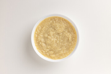 A top view of a round white bowl filled with fava bean puree, set against a white background. Simple, clean design, perfect for food styling, product mockups, or promotional use.

