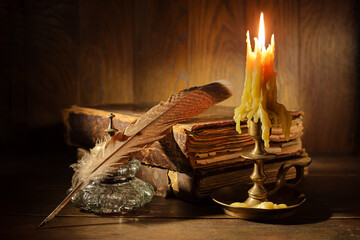 Vintage still life. Medieval table with books, candle, feather. Vintage atmosphere of antiquity.