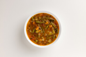 A top view of a round white bowl filled with summer vegetable minestrone, set against a white background. Simple, clean design, perfect for food styling, product mockups, or promotional use.
