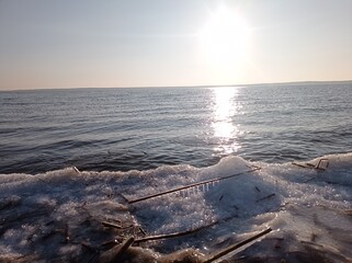 Serene Winter Seascape with Icy Shoreline and Calm Blue Waters, Capturing the Tranquility of a Frozen Beach at Sunset