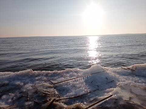 Serene Winter Seascape with Icy Shoreline and Calm Blue Waters, Capturing the Tranquility of a Frozen Beach at Sunset