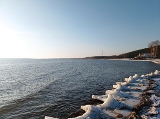 Serene Winter Seascape with Icy Shoreline and Calm Blue Waters, Capturing the Tranquility of a Frozen Beach at Sunset