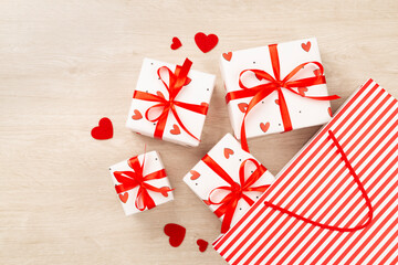 Gift boxes with red hearts on wooden background, top view