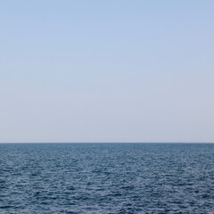 Obraz premium A calm, square shot of a late afternoon horizon with soft, muted sky colors meeting the sea, evoking a peaceful, serene atmosphere