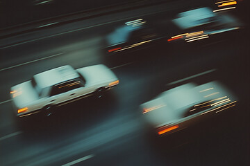 Obraz premium Night Drive: Blurred motion of cars speeding down a highway at night, creating a sense of dynamism and energy. The image is captured from a high angle, offering a unique perspective. 