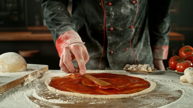 Freeze motion of pizza maker preparing fresh pizza.