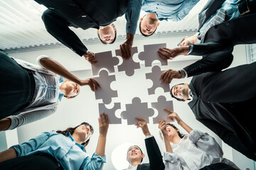 Multiethnic business people holding jigsaw pieces and merge them together as effective solution solving teamwork, shared vision and common goal combining diverse talent. Below view. Habiliment