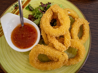 fried calamari rings on wooden cutting board served with red sauce