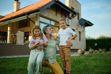Happy family posing in front of house on a sunny day