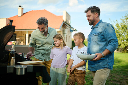 Happy family enjoying barbecue party in backyard