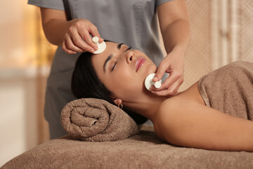 Young woman receiving facial massage with spa stones in salon