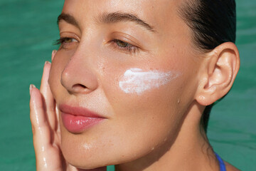 Spf, sunblock skincare cosmetics treatments. Beauty portrait of a woman with dewy skin applying...