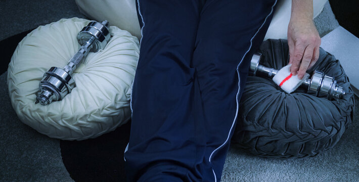 Senior man sanitizing dumbbells before home workout - Powered by Adobe