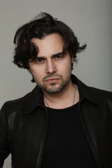 Fototapeta premium Bearded handsome man wearing black jacket and looking at the camera. Vertical.