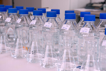 Laboratory equipment. Laboratory storage bottles with blue polypropylene cap on white table.